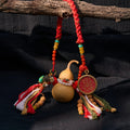 Handcrafted Tibetan amulet with gourd, braided cord, beads, tassels, and red medallion