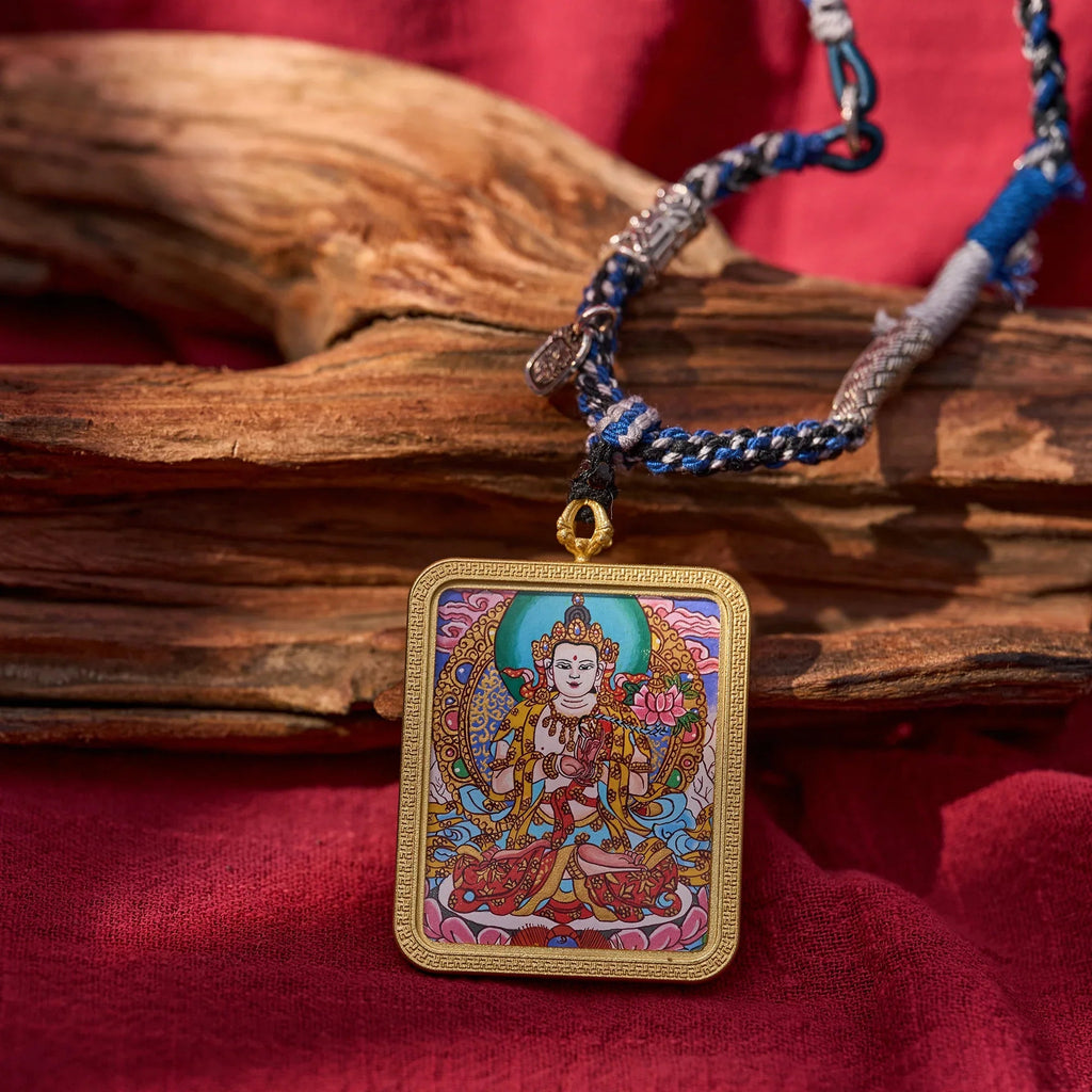 Handcrafted Tibetan deity pendant necklace with colorful braided cord on red fabric background.