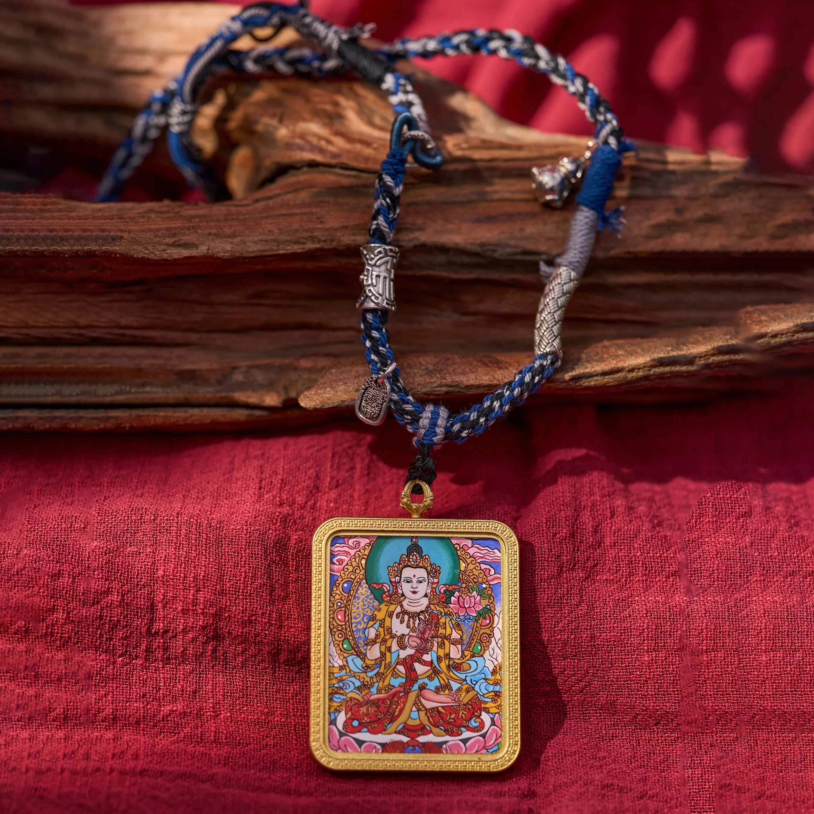 Handwoven Tibetan necklace with colorful deity pendant on red cloth backdrop