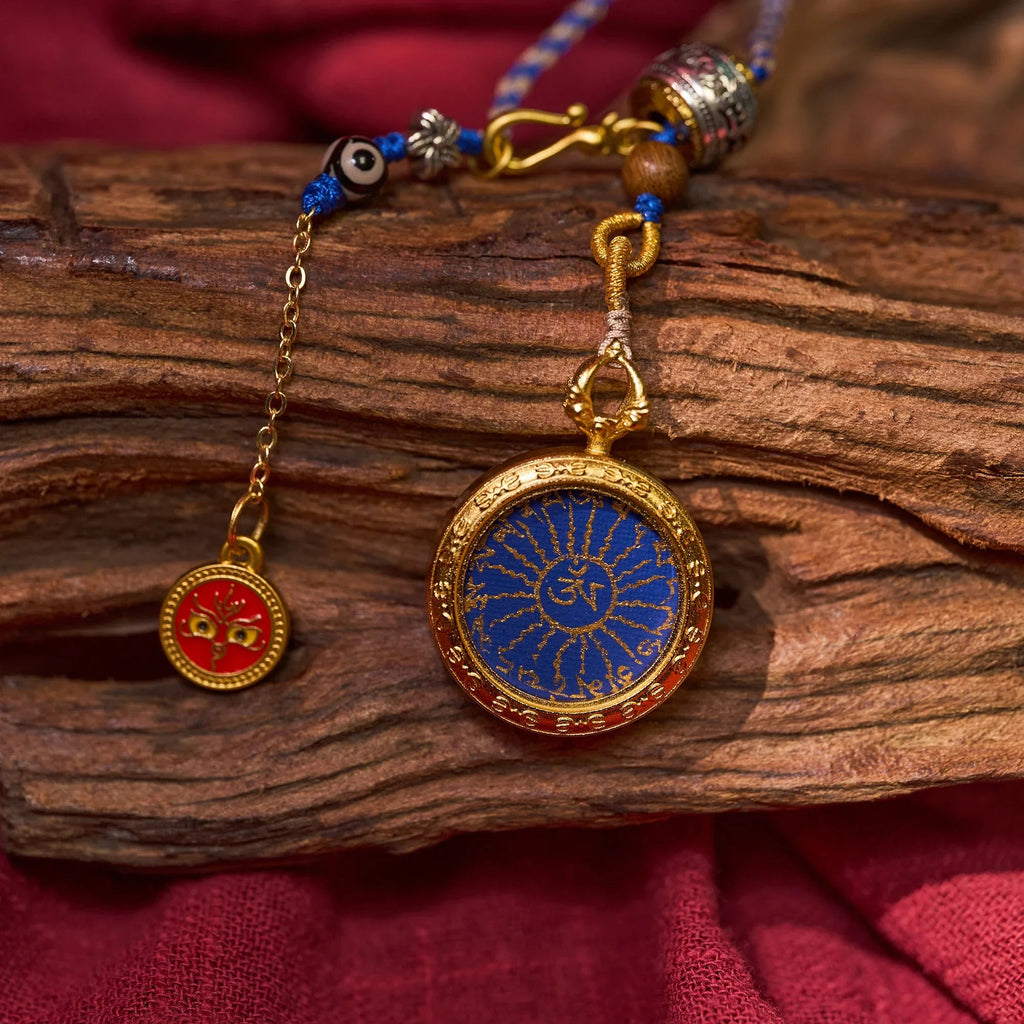Gold and blue Himalayan pendant with sacred motif and red Buddhist amulet on rustic wood