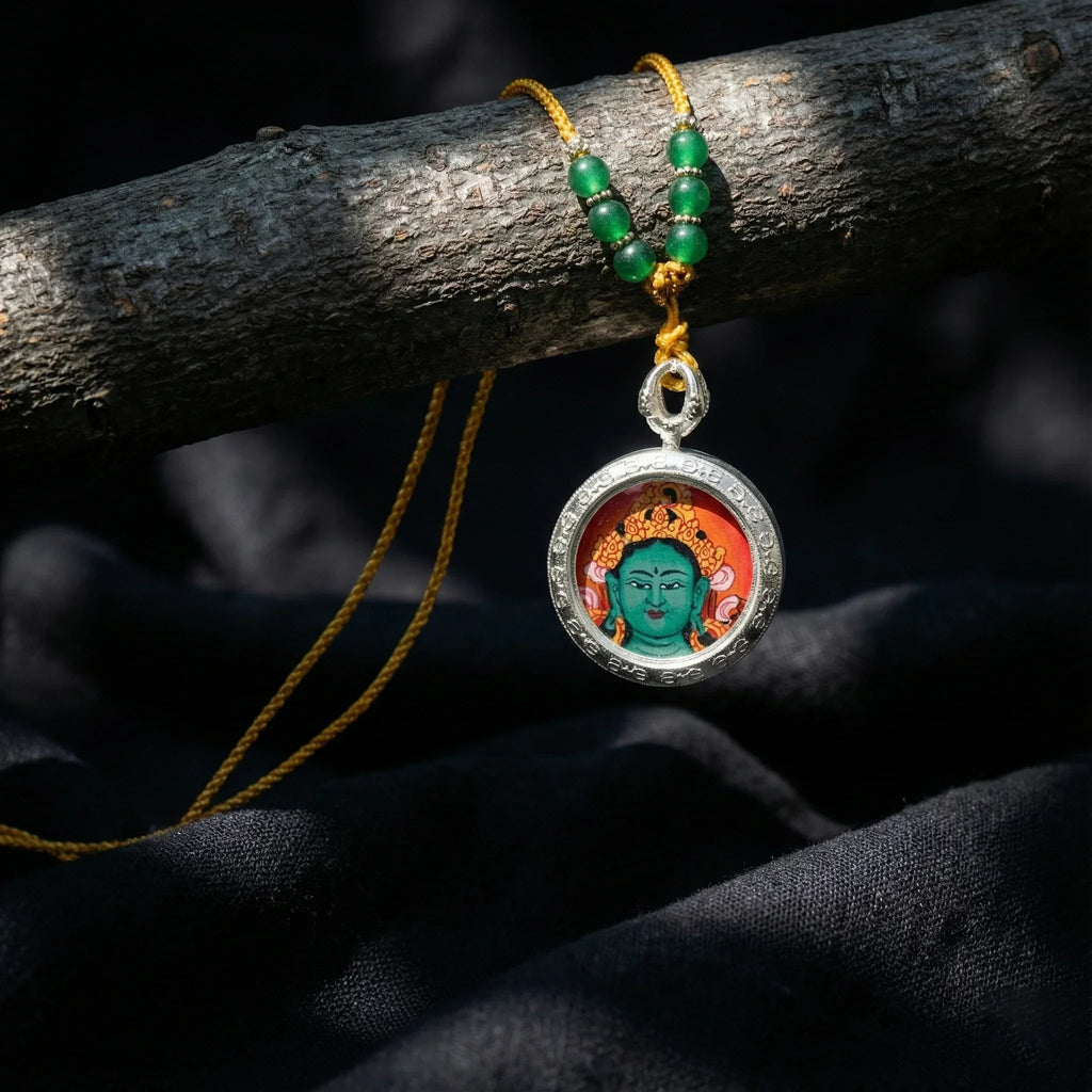 Tibetan Green Tara pendant necklace with yellow cord and green beads on dark fabric