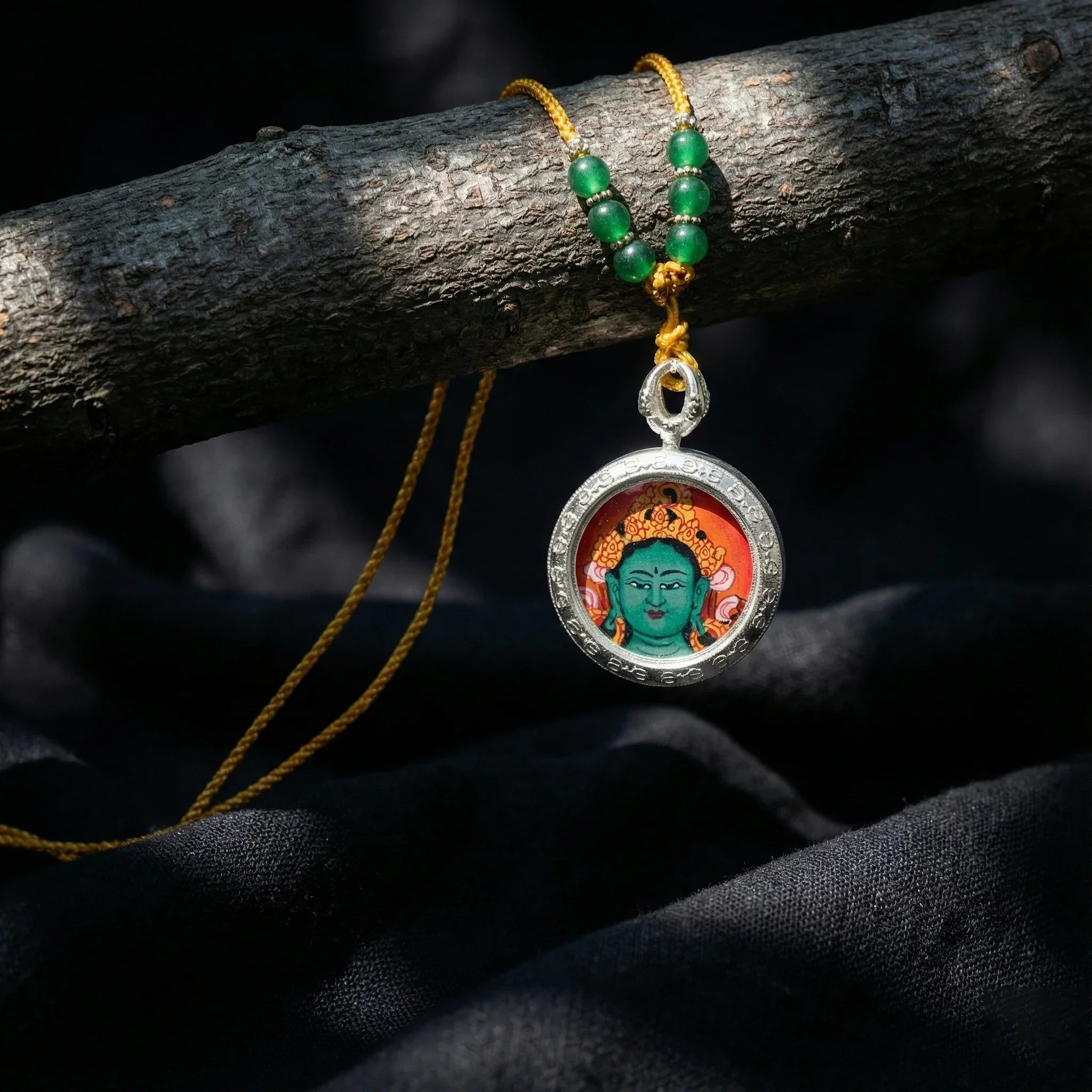 Tibetan Green Tara pendant necklace with yellow cord and green beads on dark fabric