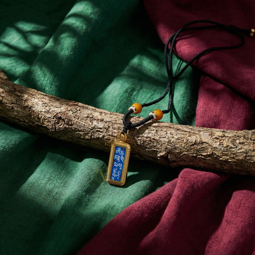 Rectangular gold and blue Tibetan amulet pendant on black cord, spiritual jewelry on fabric