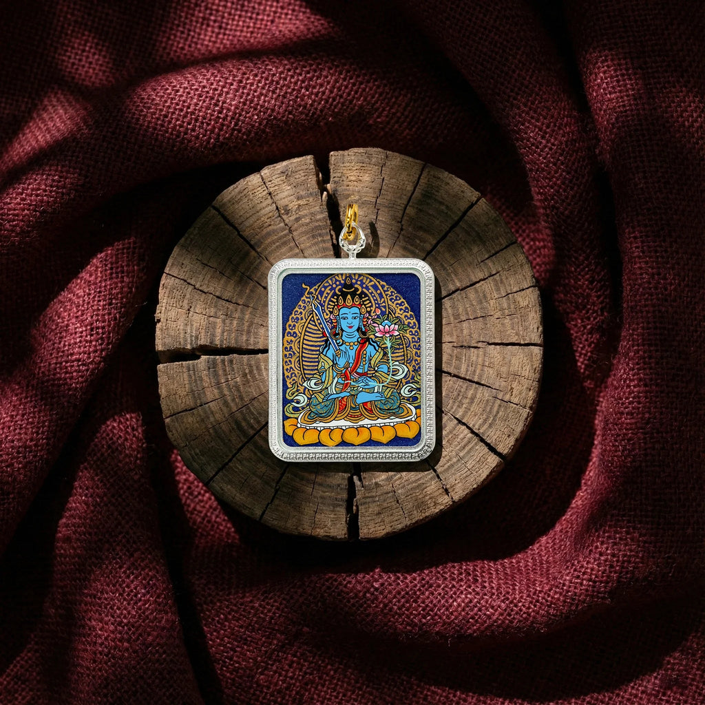 Colorful Tibetan Buddhist pendant featuring deity artwork, displayed on wood with red fabric background