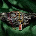 Handwoven Himalayan amulet necklace with colorful threads and Tibetan pendant on bark