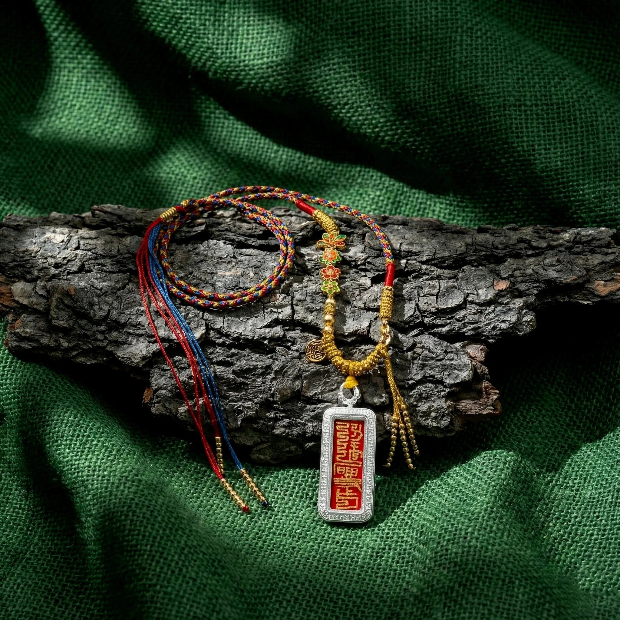 Handwoven Himalayan amulet necklace with colorful threads and Tibetan pendant on bark