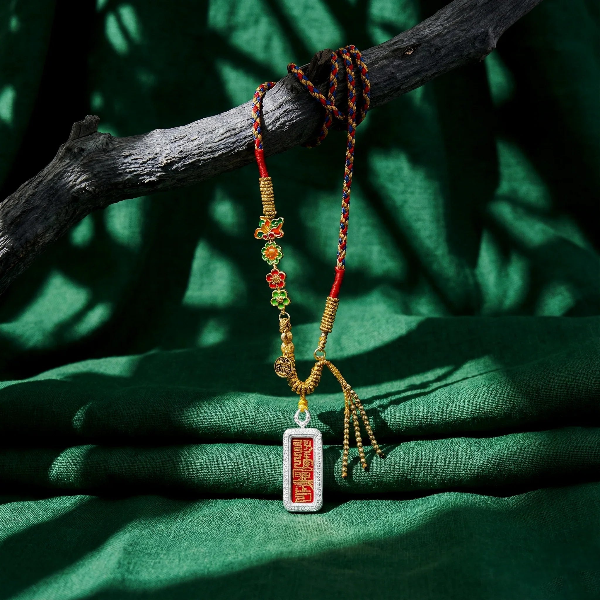 Colorful braided Himalayan pendant necklace with floral charms and engraved red tag on green fabric