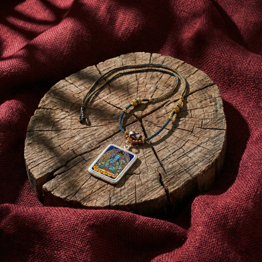 Tibetan Buddhist pendant necklace with colorful deity artwork on woven cord, displayed on rustic wood.