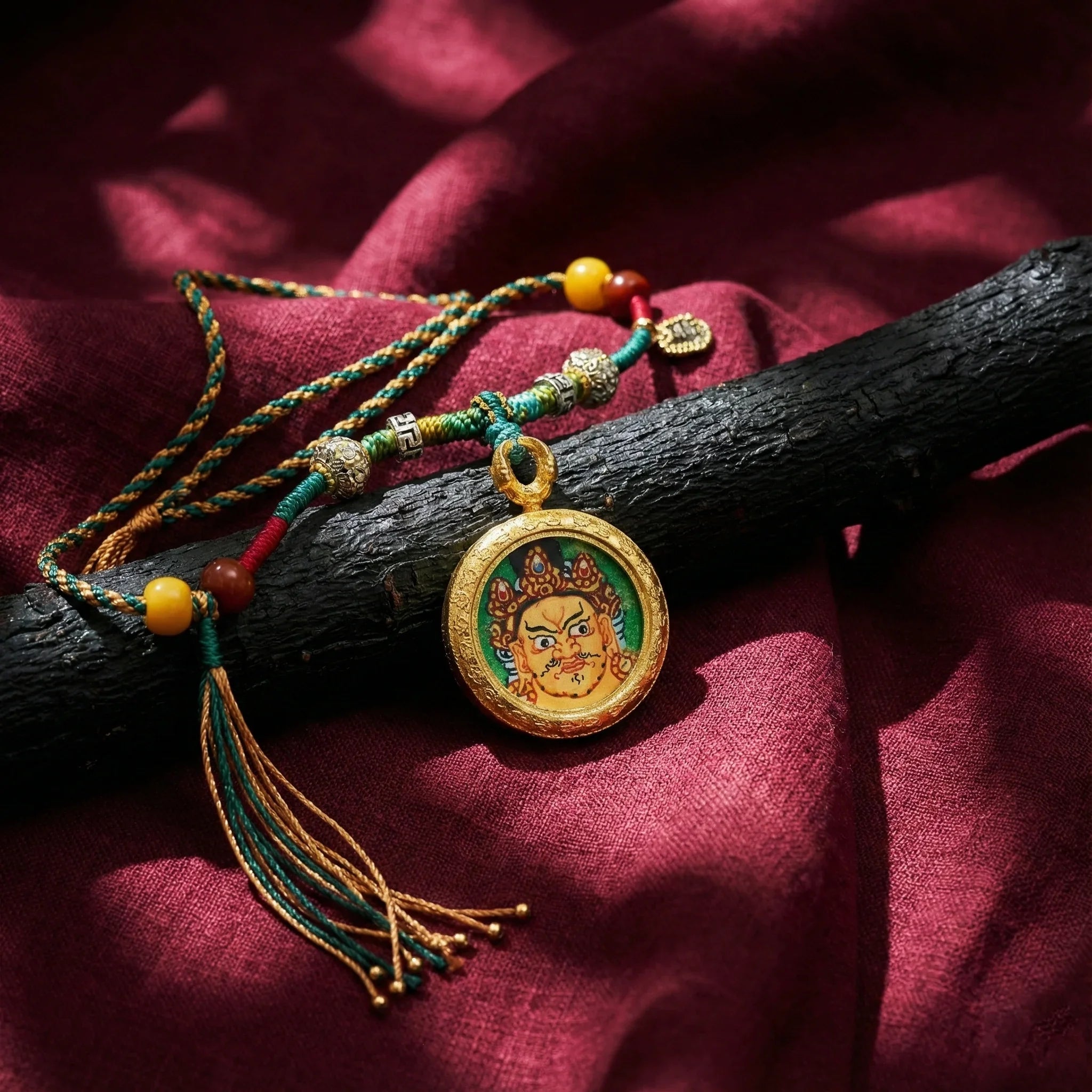 Tibetan-style pendant necklace with deity motif, colorful braided cord, on red fabric
