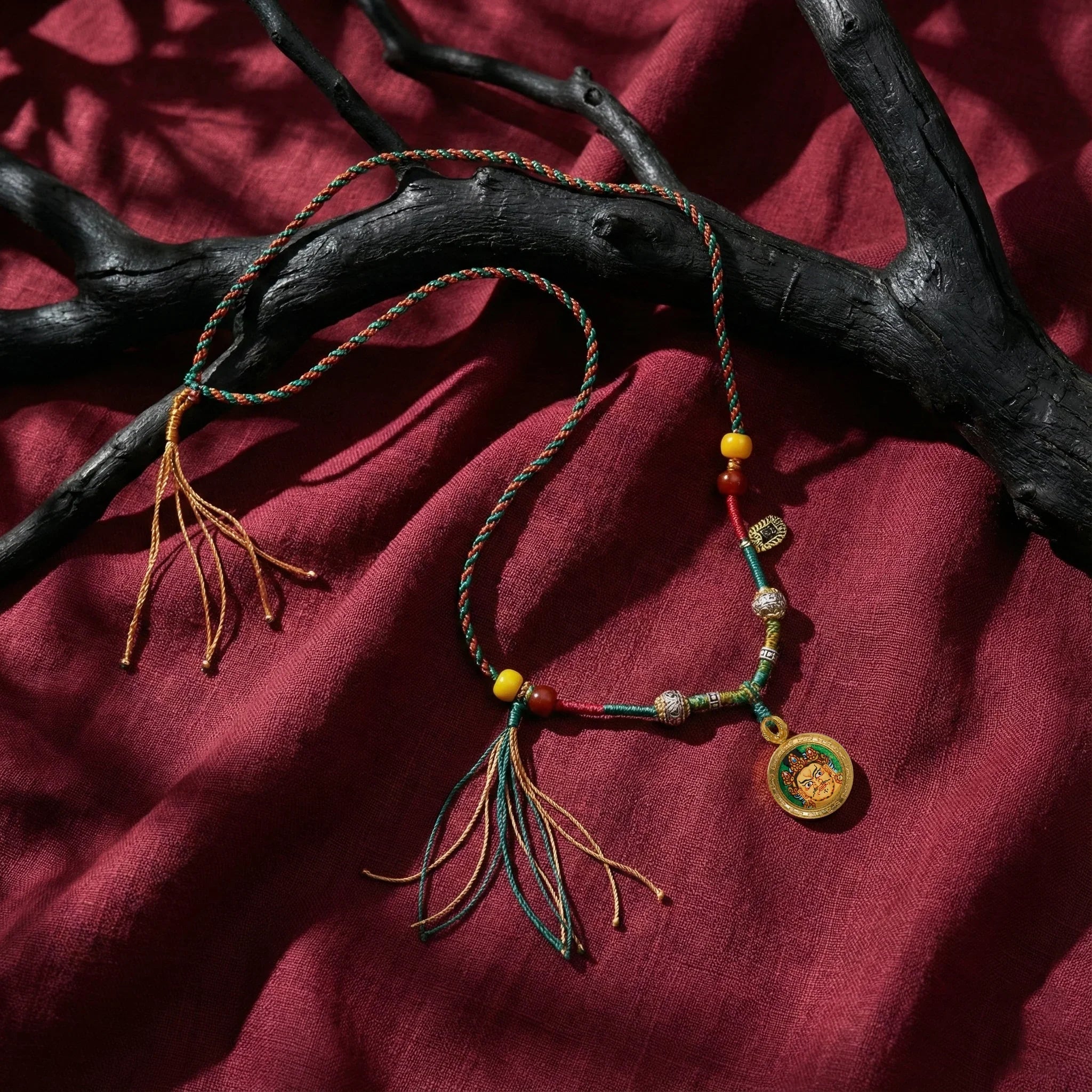 Handwoven Tibetan-style necklace with colorful beads and medallion on red fabric background
