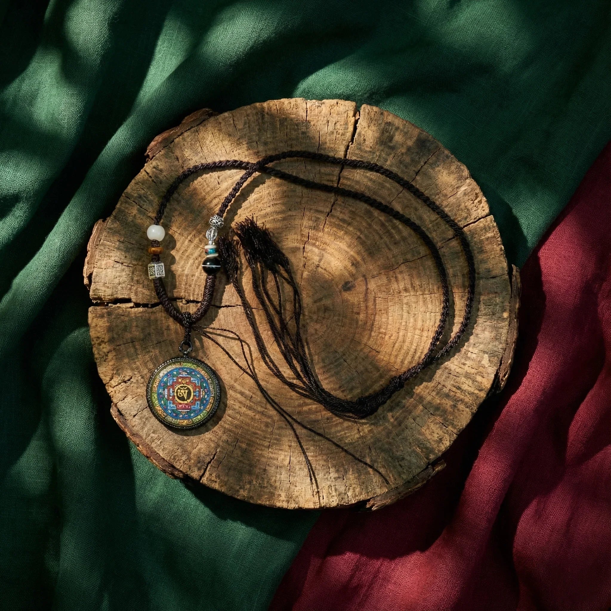 Handcrafted Tibetan mandala necklace with beads on wood slice, green and red fabric background